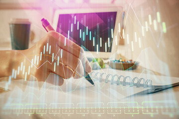 Financial forex graph drawn over hands taking notes background. Concept of research. Multi exposure
