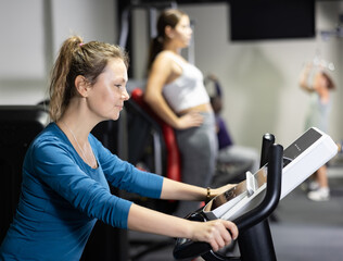 Sporty woman doing cardio workout out, training on exercise bike