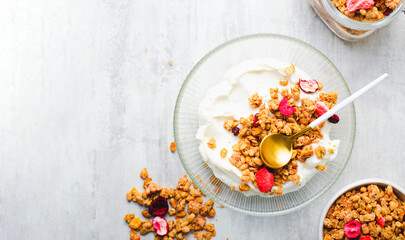 Obraz na płótnie Canvas Granola with Yogurt in a Boal, Healthy Breakfast, Muesli with Dried Berries on Bright Concrete Background