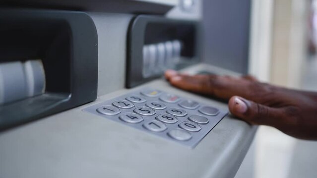 Close up shot of a man typing his PIN code on a keyboard of a ATM to withdrawal money from bank