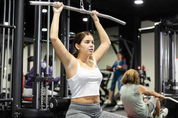 Fototapeta na wymiar Caucasian woman doing reps on lat pull down machine in gym