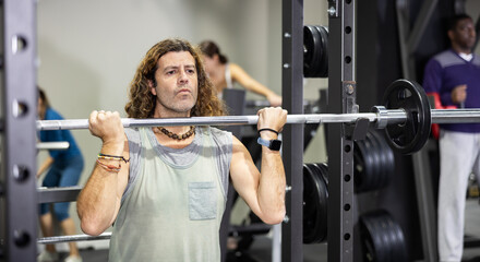 Fototapeta na wymiar Muscular man doing barbell exercises in the gym