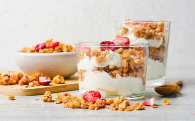 Granola and Yogurt Parfaits, Healthy Breakfast or Snack, Muesli with Dried Berries on Bright Concrete Background