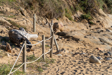 Wooden fence on the beach with yellow sand and rocks