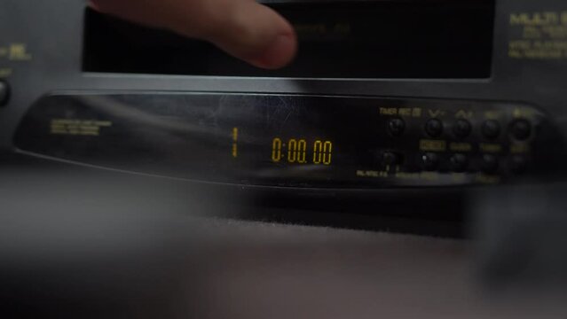 Inserts a video cassette into a VCR and presses the button and eject VHS