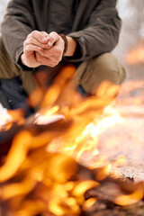 Man warming hands on bonfire in nature in cold season, winter. travel lifestyle photo. adventure active vacations outdoor. camping. in snowy frozen forest alone. close-up focus on hands