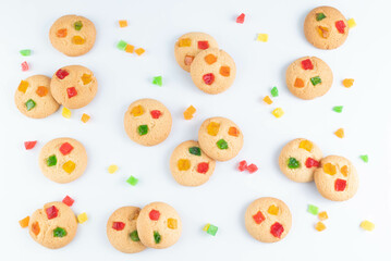 Round cookies with candied fruits are laid out on a white background.