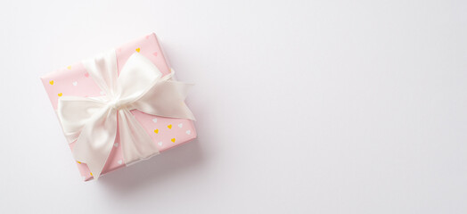 Saint Valentine's Day concept. Top view photo of pastel pink present box with silk ribbon bow on isolated white background with copyspace