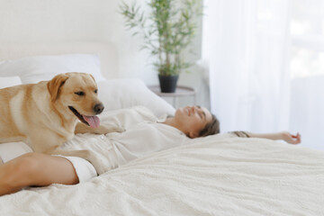 girl in white clothes with dog labrador playing at home