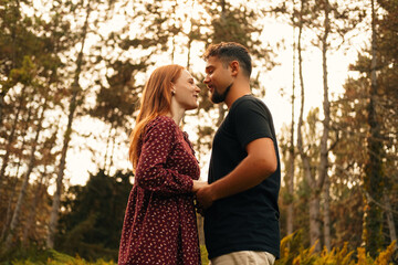 Fototapeta premium Cheerful young couple are smiling and looking at each other in the eyes.