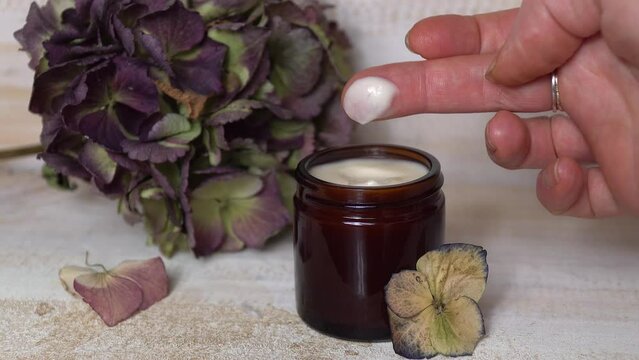 Woman taking the natural face carem on her finger. Homemade skin moisturizer.