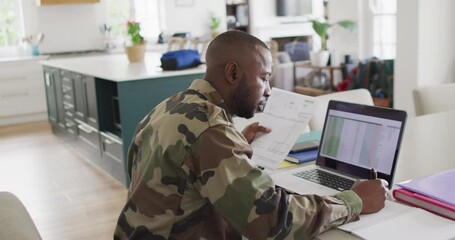 African american father with son sitting at table and working