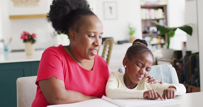 Video of smiling african american grandmother listening to her granddaughter reading braille