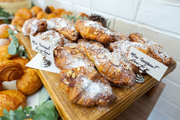 close up of croissant served on a wooden table. variety of different breads in a bakery.