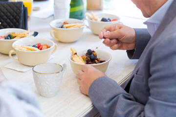 Man eating a dessert fruits bowl with many dessert bowls on a table. Close up of an elegant meal.