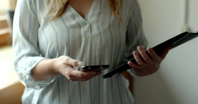 An unrecognizable female social worker uses phone to perform her professional duties. Woman call the client to confirm the appointment. Online coordination volunteering.