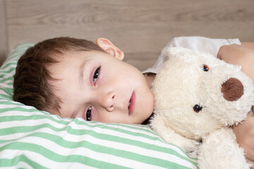 Unhealthy little boy child sleep in bed relax at home in bedroom. Sick ill little kid suffer from flu fever asleep in bed on lockdown quarantine