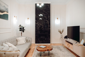 Stylish pastel apartment, Details of luxurious sofa, wooden tv table, golden light fixtures and fireplace wall