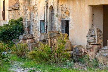 Fototapeta na wymiar Pilaster and ashlar of the main church, preserved and stacked for rebuild, in the ruins of the village Poggioreale, a ghost town in the western Sicily. 