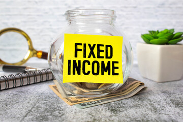 The word fixed income in English written on a piece of paper over a blue calculator and a pen in the composition.