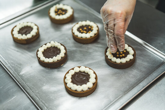 closeup view of a baker's hand adding golden sprinkles to the chocolate cakes at the bakery. High quality photo