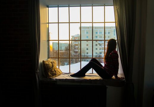 Side view of woman sitting on alcove window seat