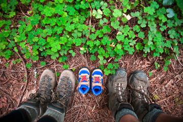 Expecting parents use a pair of small hiking boots in line with their own to announce the arrival of their new baby.