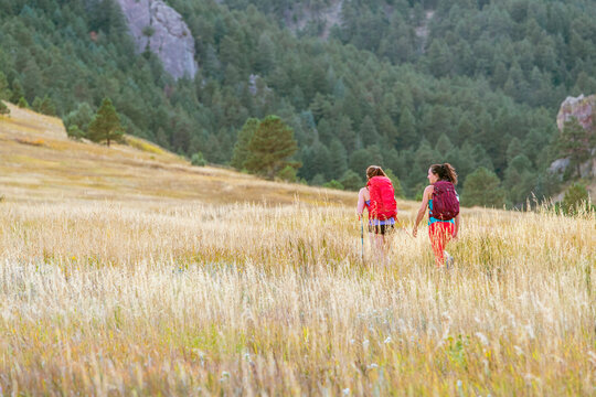 female hikers walk on a trail beneath the flatirons in Colorado