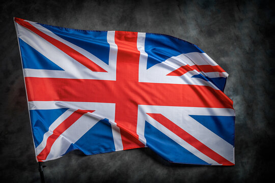 The UK Flag Waving In The Wind Against A Dark Background.