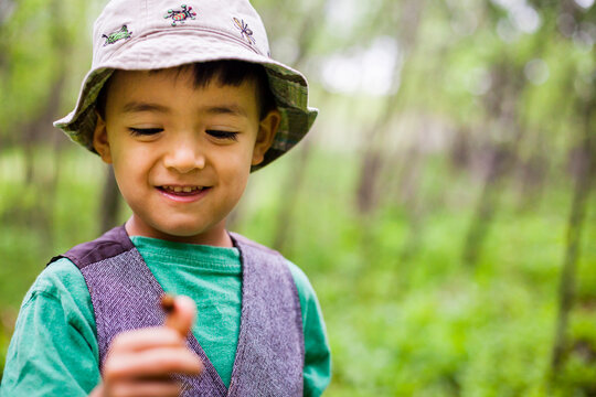 Boy standing in forest and holding bug on finger