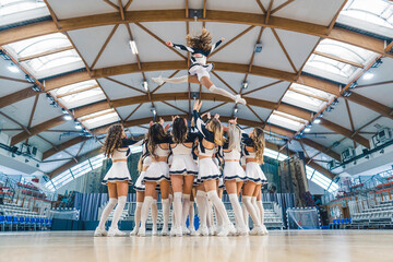 A group of cheerleaders are captured in a dynamic and athletic moment, performing a stunt by...