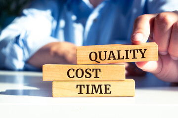 Closeup on businessman holding a wooden block with "Quality, Cost and Time" message, Business concept