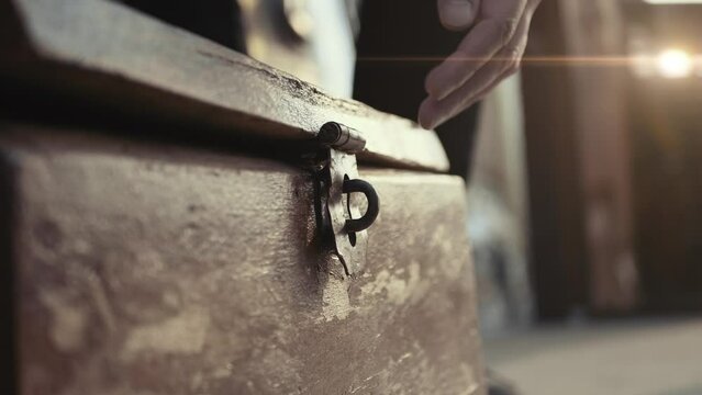 Man hand opens lid of vintage wooden chest.
