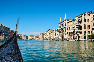 View of the Grand Canal in Venice, Italy. Panoramic view from gondola, Venetian cityscape with facades of picturesque old buildings on sunny spring day with cloudless blue sky, plenty of copy space