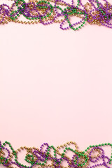 Frame of Mardi Gras beads on pink background. Greeting card template, poster, vertical banner design.