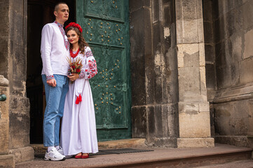Portrait of a happy young couple in love, a family hugging, holding hands in the city of Lviv in traditional Ukrainian shirts, holding hands. Young people hug in the old town of Lviv