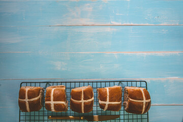 Easter Hot Cross Buns cooling on a wire rack. blue whitewash coloured background