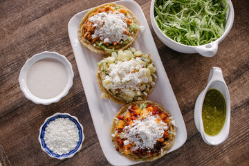 Sopes de guisado con lechuga, crema, queso y salsa 