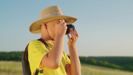 Happy boy, child dreams of becoming photographer. Boy plays with camera, takes pictures of landscape in summer park. Child dreams of traveling, making discoveries. Children's fantasy in nature.