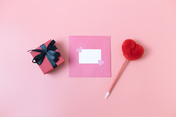Envelope, gift box and heart pen on a pink background.