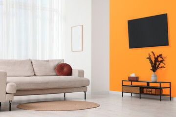 Stylish sofa near orange wall in room. Interior design