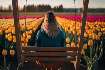 Fotobehang woman sitting in front of a tulip field © ThisDesign