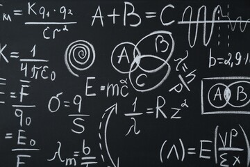 Different physical formulas written with chalk on blackboard, closeup