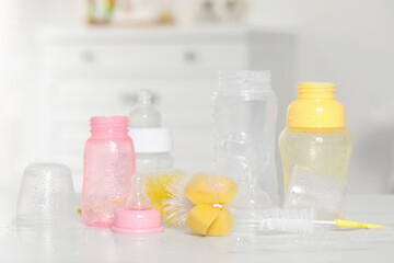 Clean baby bottles with nipples after sterilization and cleaning tools on white table indoors