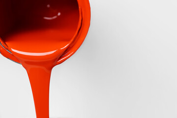 Pouring orange paint from can on white background, closeup. Space for text