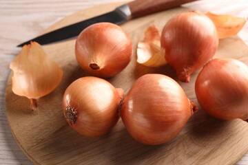 Obraz premium Tray with ripe onions and knife on wooden table, closeup