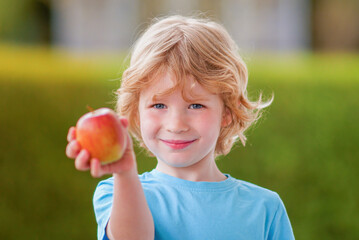 Portrait of young blonde caucasian boy with apple