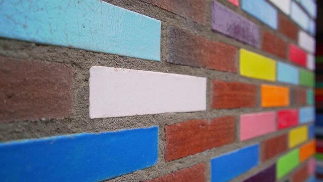 Colourful decorative bricks laid in a red brick outside wall of a building