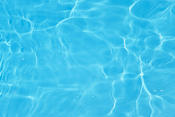 Obraz premium Defocus blurred transparent blue colored clear calm water surface texture with splashes and bubbles. Trendy abstract nature background. Water waves in sunlight with caustics. Blue water shinning 