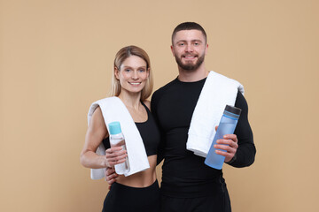 Athletic people with bottles of water and towels on light brown background